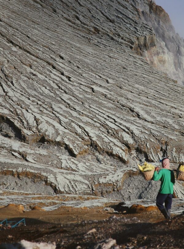 a man carrying a surfboard on top of a mountain