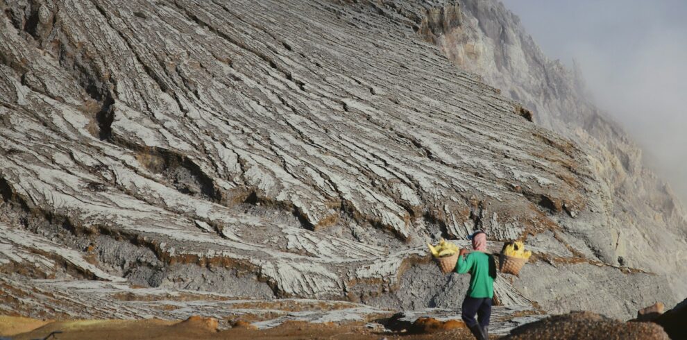 a man carrying a surfboard on top of a mountain